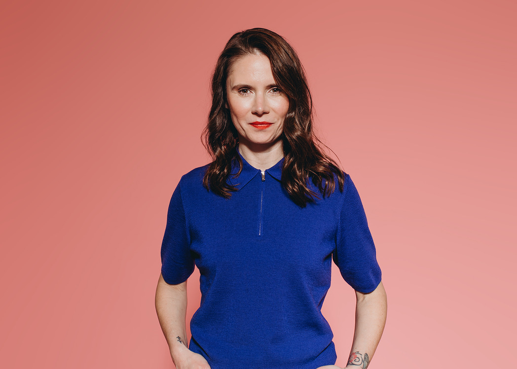 Agathe Hütter im blauen Oberteil vor korallfarbenem Hintergrund
