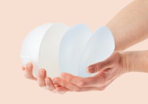 Zwei weibliche Hände halten behutsam Brustimplantate – Symbolbild für Entscheidung und Verantwortung bei ästhetisch-chirurgischen Eingriffen